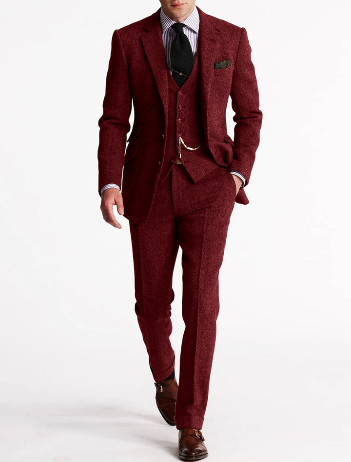 Stylish man modeling a classic brown herringbone three-piece suit; ideal for business & formal occasions.