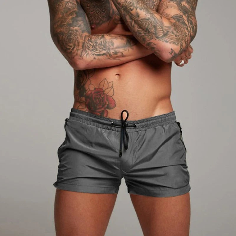 "Men's quick-dry, stretchy swim shorts with pockets in vibrant colors, featuring an elastic waistband and sleek design."