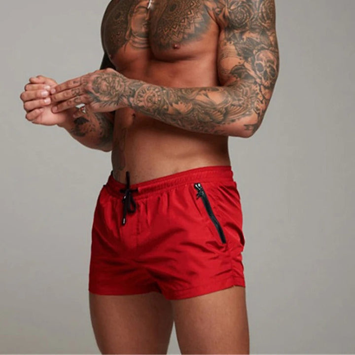 "Men's quick-dry, stretchy swim shorts with pockets in vibrant colors, featuring an elastic waistband and sleek design."