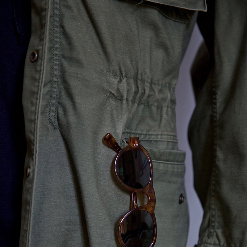 "Men's vintage military jacket with hidden hood, snap-button cargo pockets, wind-resistant, rugged style."