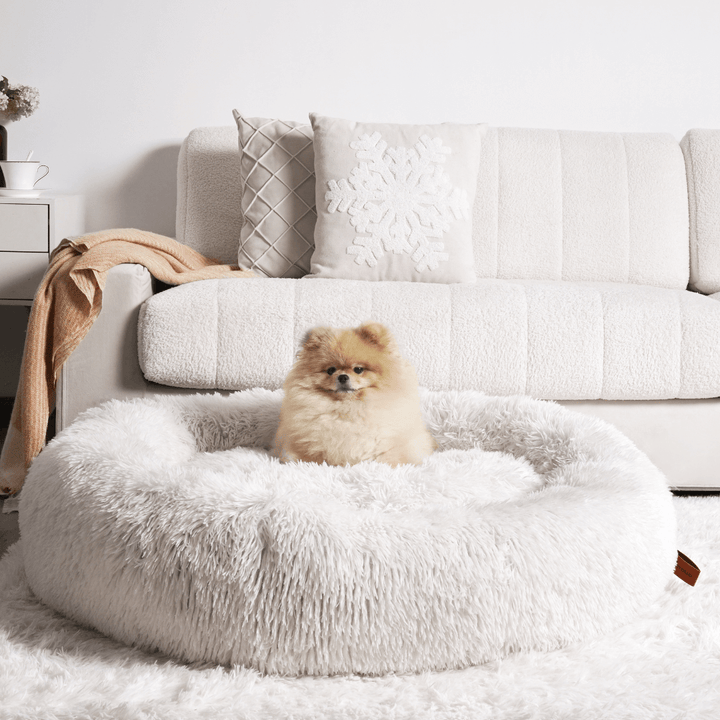 "Plush apricot donut dog bed, anxiety-relieving, round with raised rim, faux fur, for dogs to curl up comfortably."