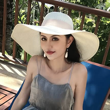 Vacation-ready women's wide brim straw sun hat with a decorative bow for stylish beach protection.
