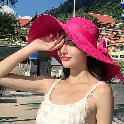 Elegant women's wide brim straw beach hat with a stylish bow detail for summer vacation fashion.
