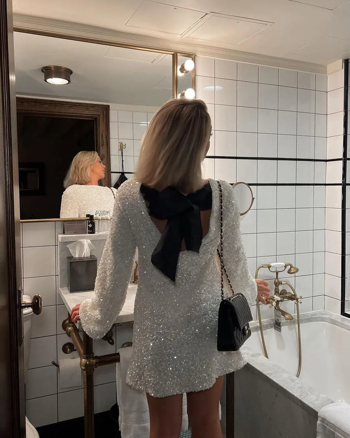Elegant sleeveless sequin dress with festive sparkle & a chic back bow, ideal for parties.