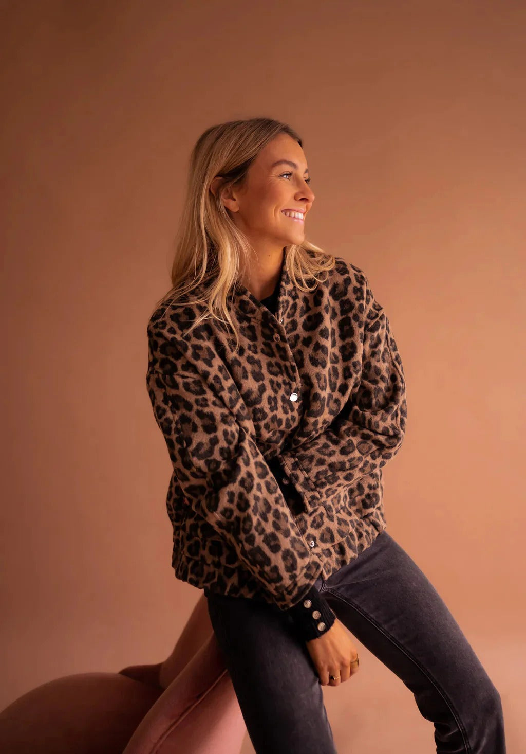 Fashionable women's brown leopard print bomber jacket. Trendy animal print outerwear with snap buttons for transitional wear.