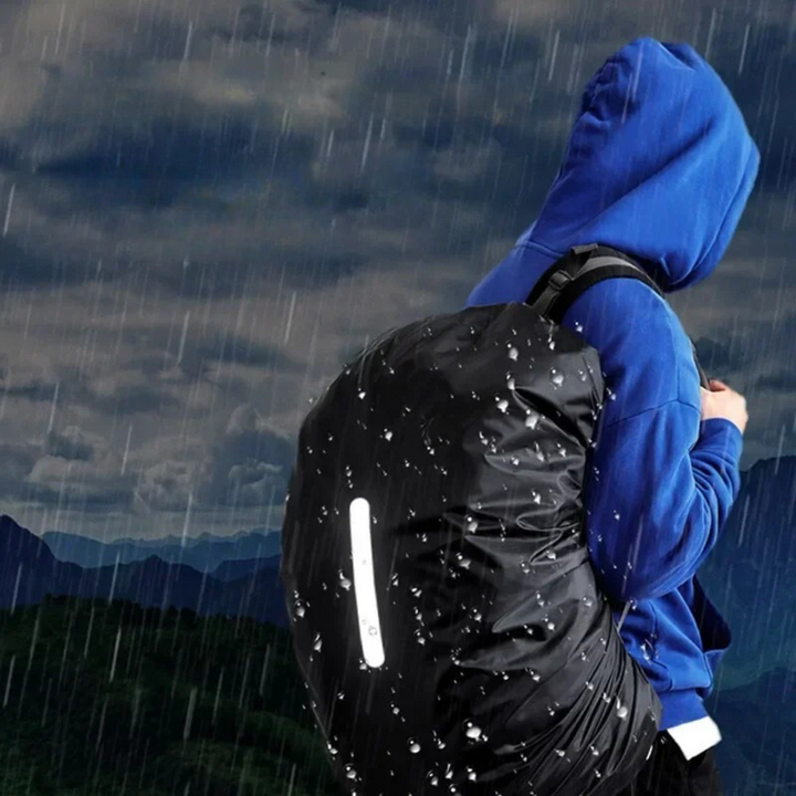 Bright reflective lightweight rain cover securely fitted on a black backpack in daylight.
