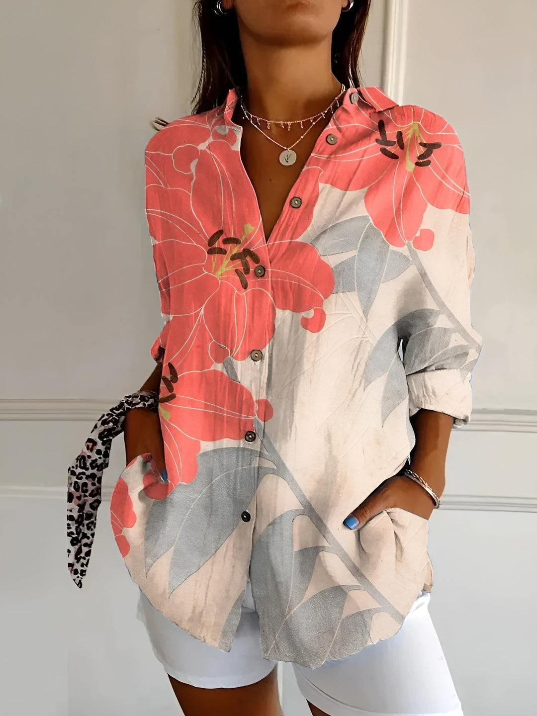 Close-up of a women's printed button-front blouse collar and rolled three-quarter cuff. Patterned top.