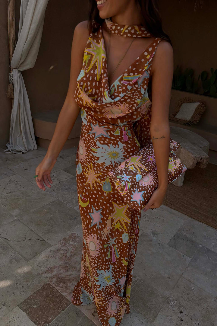 Woman twirling in flowy brown fawn print cowl neck halter maxi dress, showcasing movement.