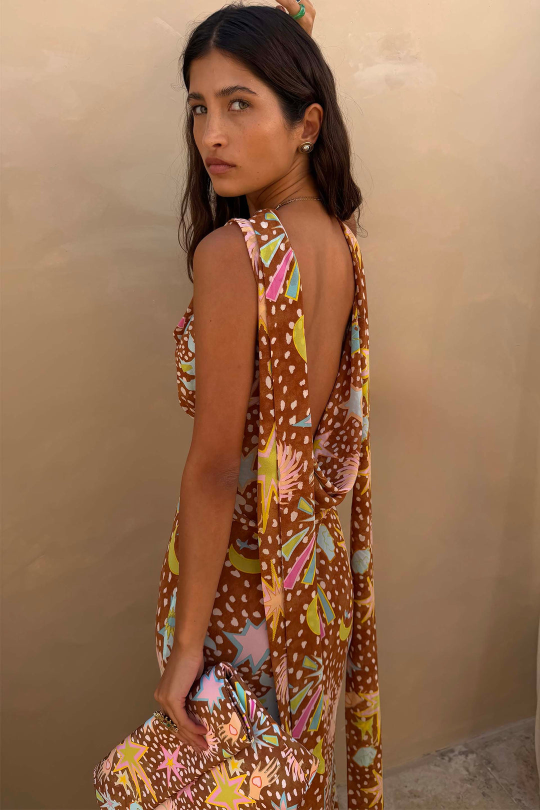 Side view highlighting the elegant bias cut of the brown fawn print cowl neck halter maxi dress.