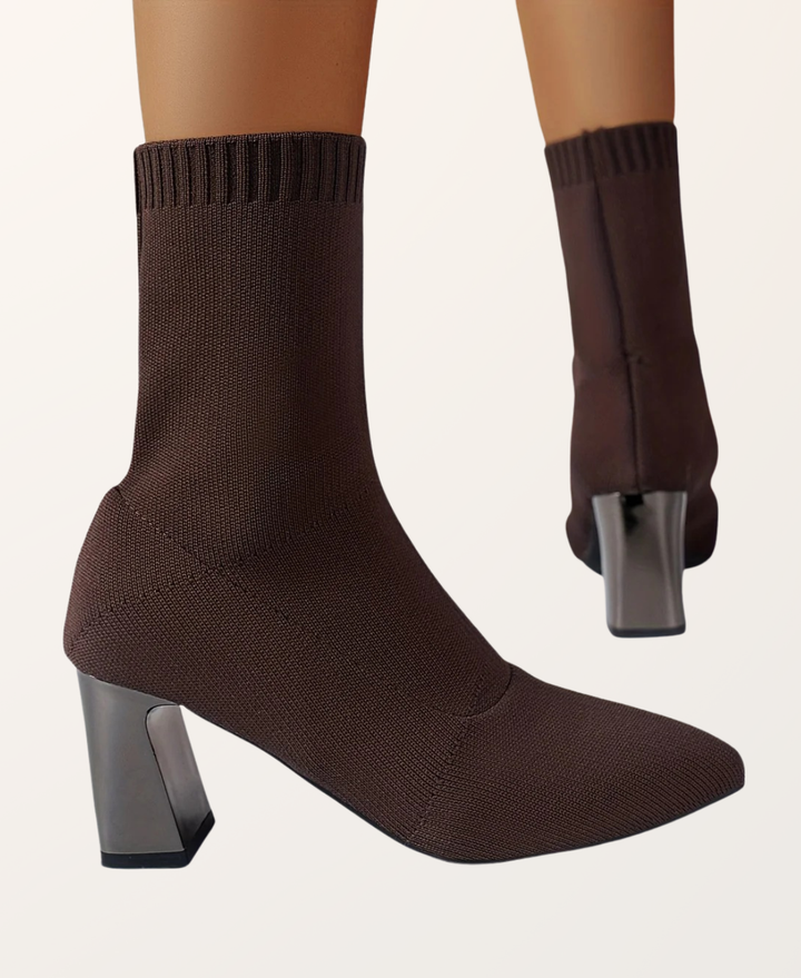 Close-up of a women's black pointed toe sock boot with a sleek block heel. Elegant pull-on footwear design.