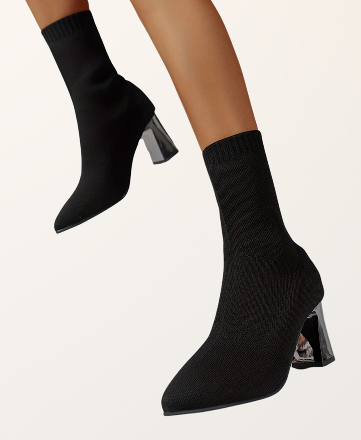 Woman wearing elegant black high heel sock boots with a block heel, styled for a chic look. Day-to-night footwear.
