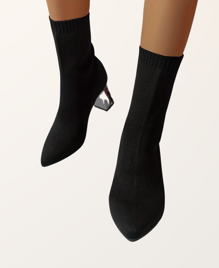 Detail shot of the block heel on women's black high heel sock boots, emphasizing stability & style. Formal/casual.