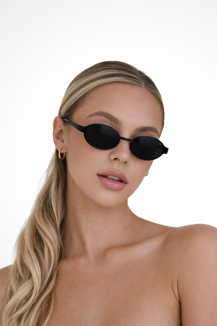 Minimalist women's oval sunglasses, featuring a sleek metal frame and dark tint lenses for modern style.