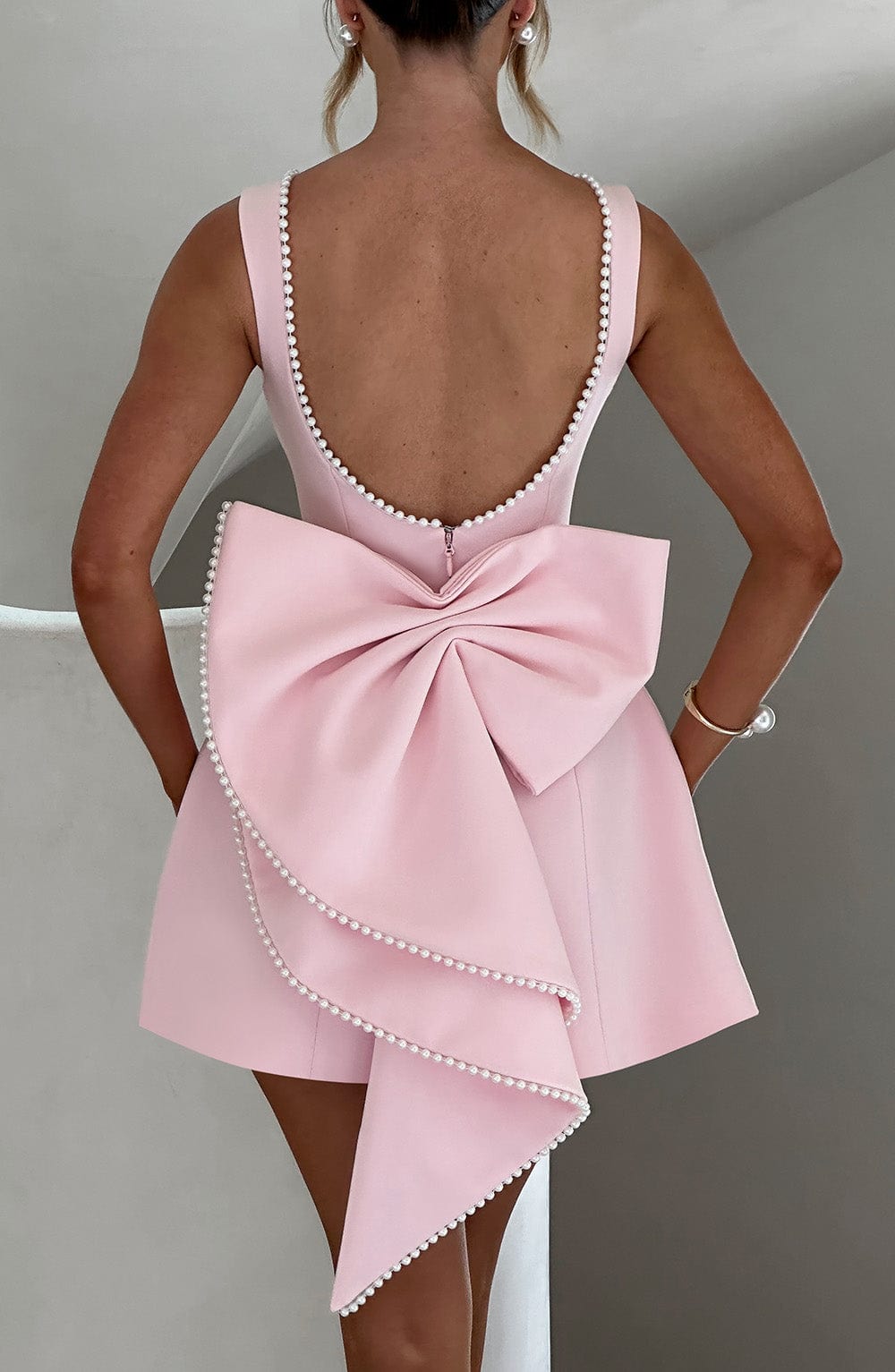 Stylish women's A-line mini dress with bow back & pearl trim. Elegant wedding guest or party dress.