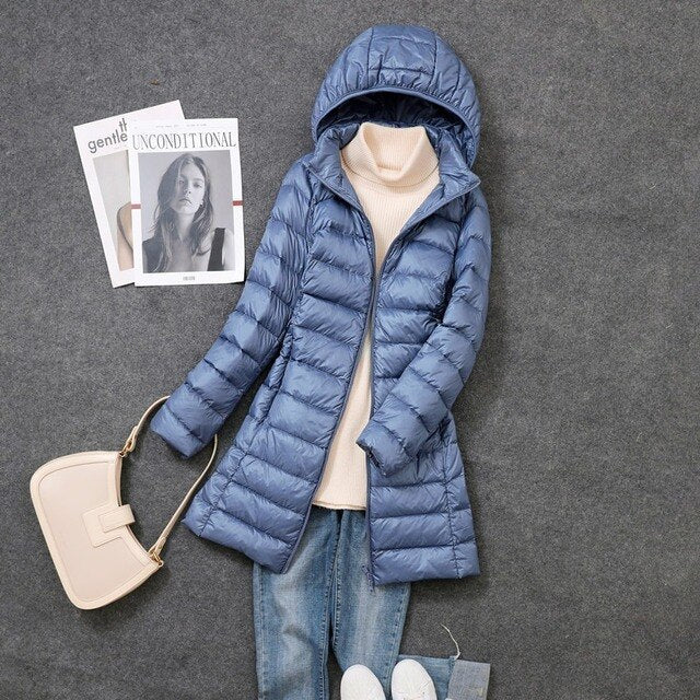 Stylish women's long puffer jacket for cold weather. Features a warm design and a practical detachable hood.
