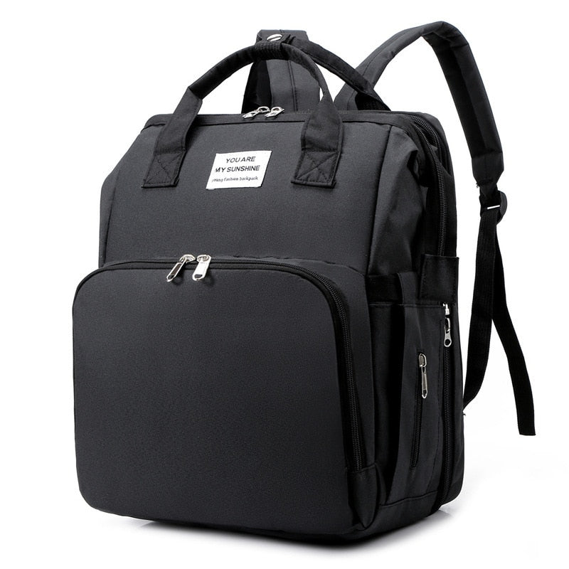 Women's multi-function diaper backpack with integrated portable baby bed for on-the-go parents.