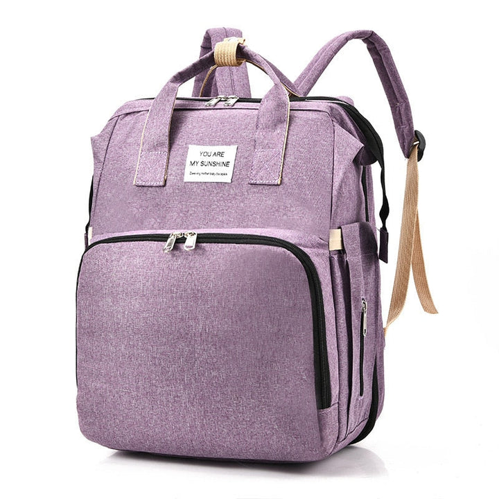 Versatile multi-function diaper bag backpack with portable infant sleeper bed for travel.