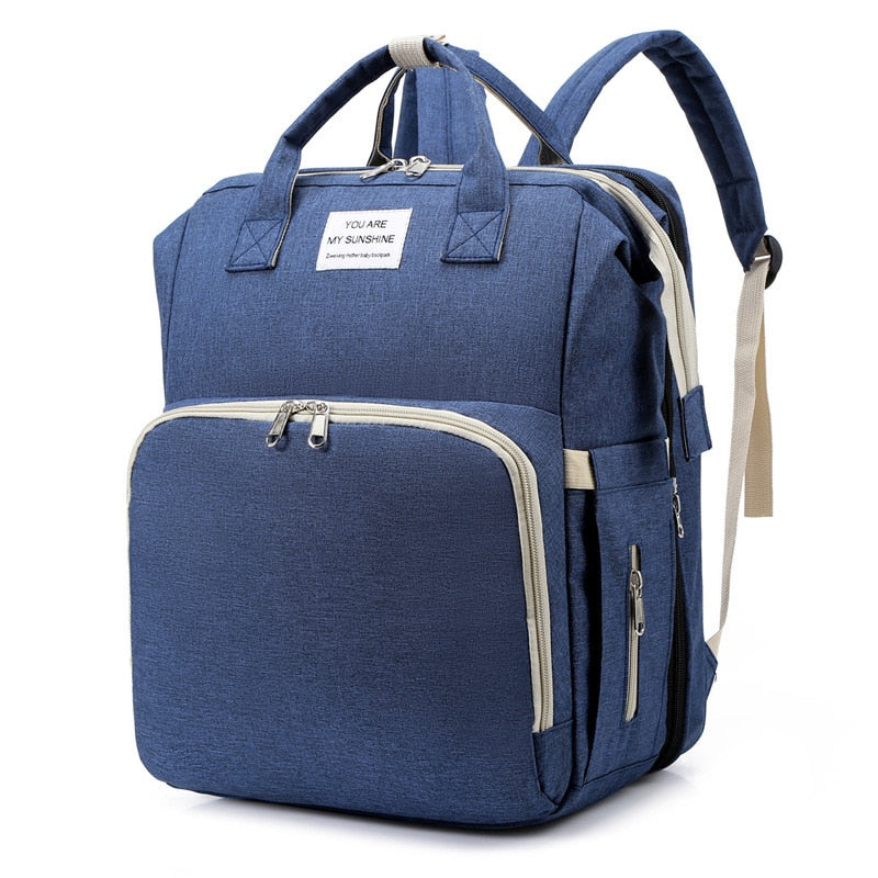 Portable baby bed and nappy bag travel backpack, essential for infant travel and diaper changes.