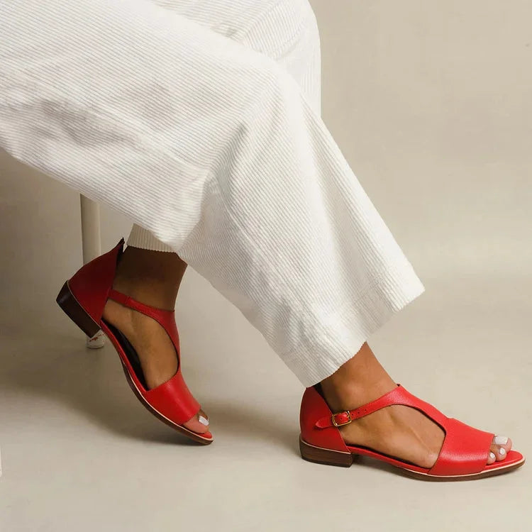 Women's red flat sandals with T-strap, open-toe design, and adjustable buckle. Comfortable summer footwear.
