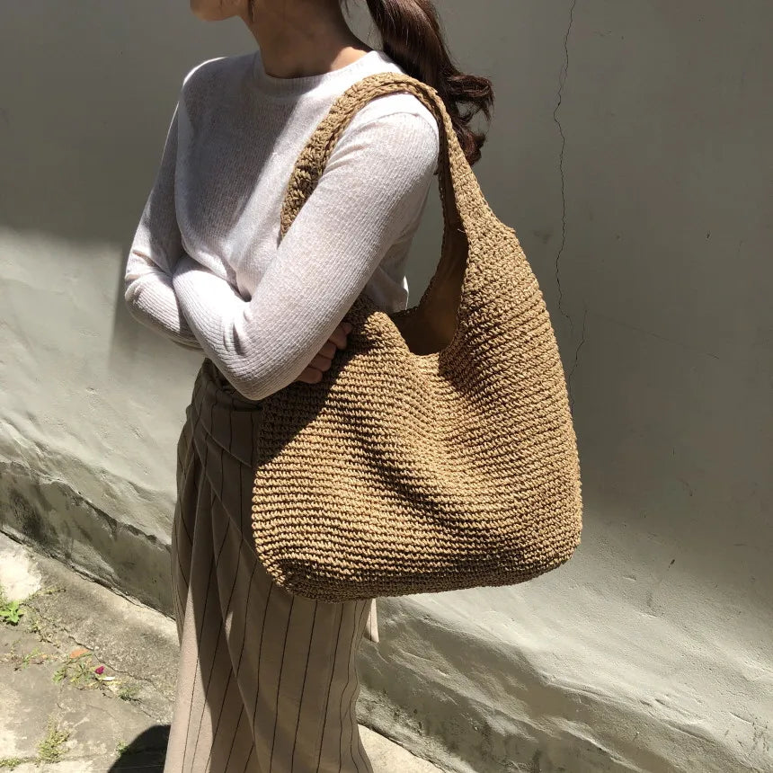 Handwoven women's straw hobo bag with a comfortable shoulder strap. Ideal summer accessory for beach & vacation.