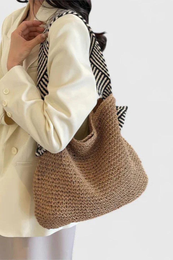 Spacious women's woven straw tote bag with fashionable contrast straps, great for casual everyday use.