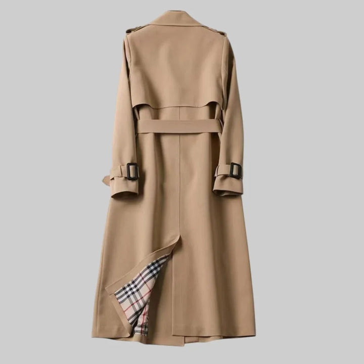 Fashionable women's classic beige trench coat, double-breasted and belted, offering an elegant, timeless look.
