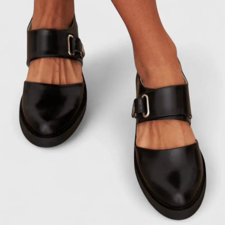 Classic black Mary-Jane flats with unique side cut-outs for women. Comfortable footwear ideal for elegant everyday style.