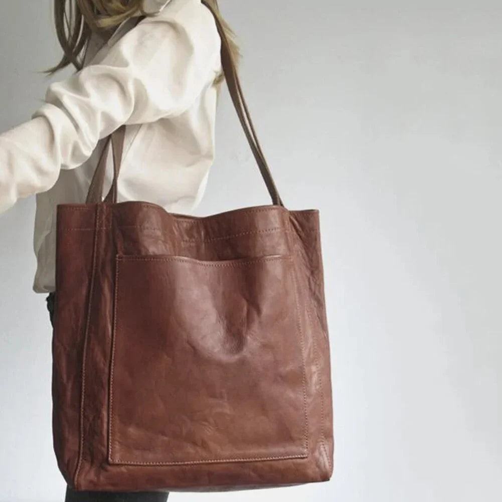 Chic women's brown leather accessory tote bag with a sleek design, magnetic closure, and practical front pocket.