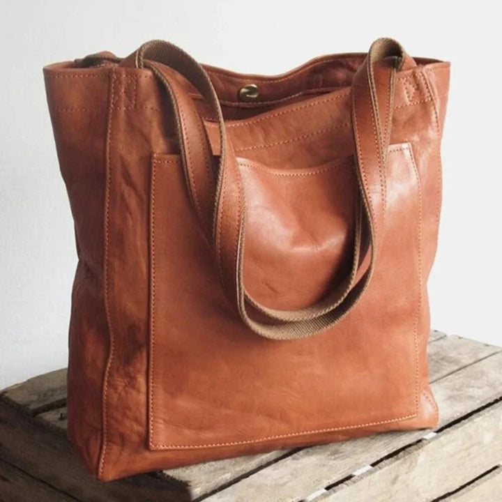 Stylish women's brown leather tote bag with magnetic snap closure and convenient front patch pocket, perfect for everyday.