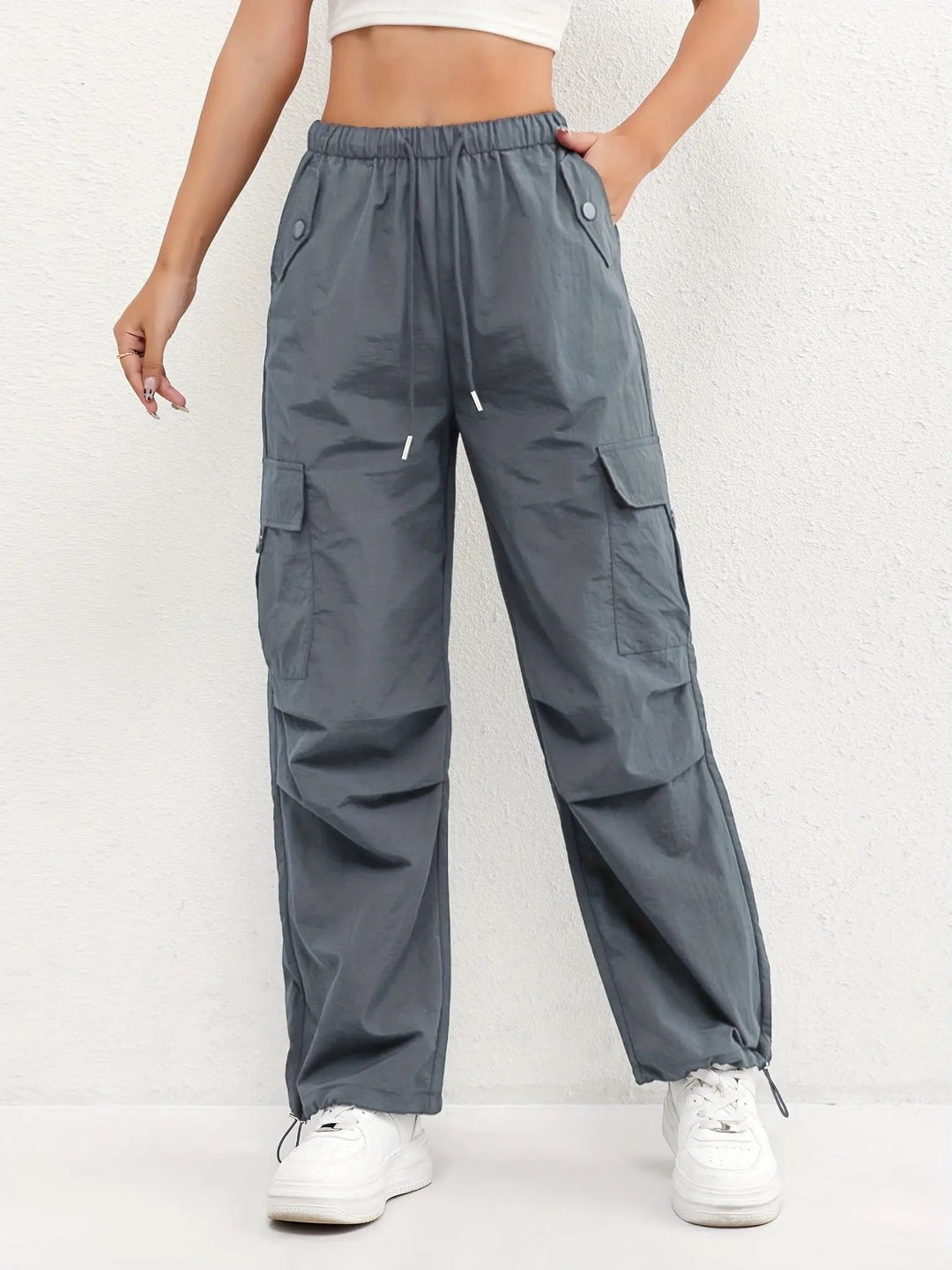 Woman models casual street style parachute cargo pants, featuring multi-pockets & comfortable adjustable waist.