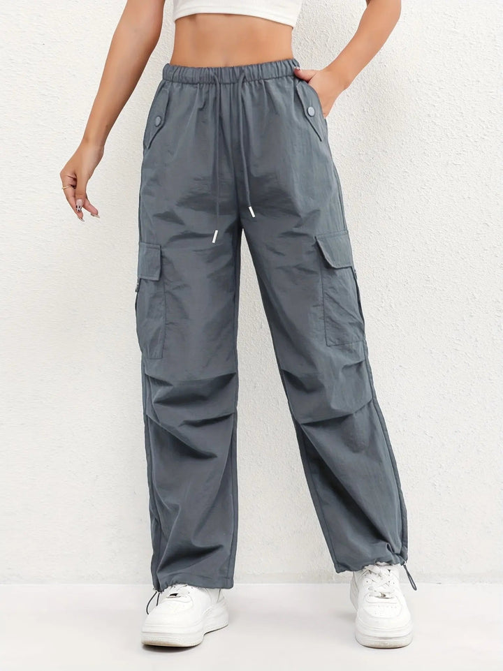 Woman models casual street style parachute cargo pants, featuring multi-pockets & comfortable adjustable waist.