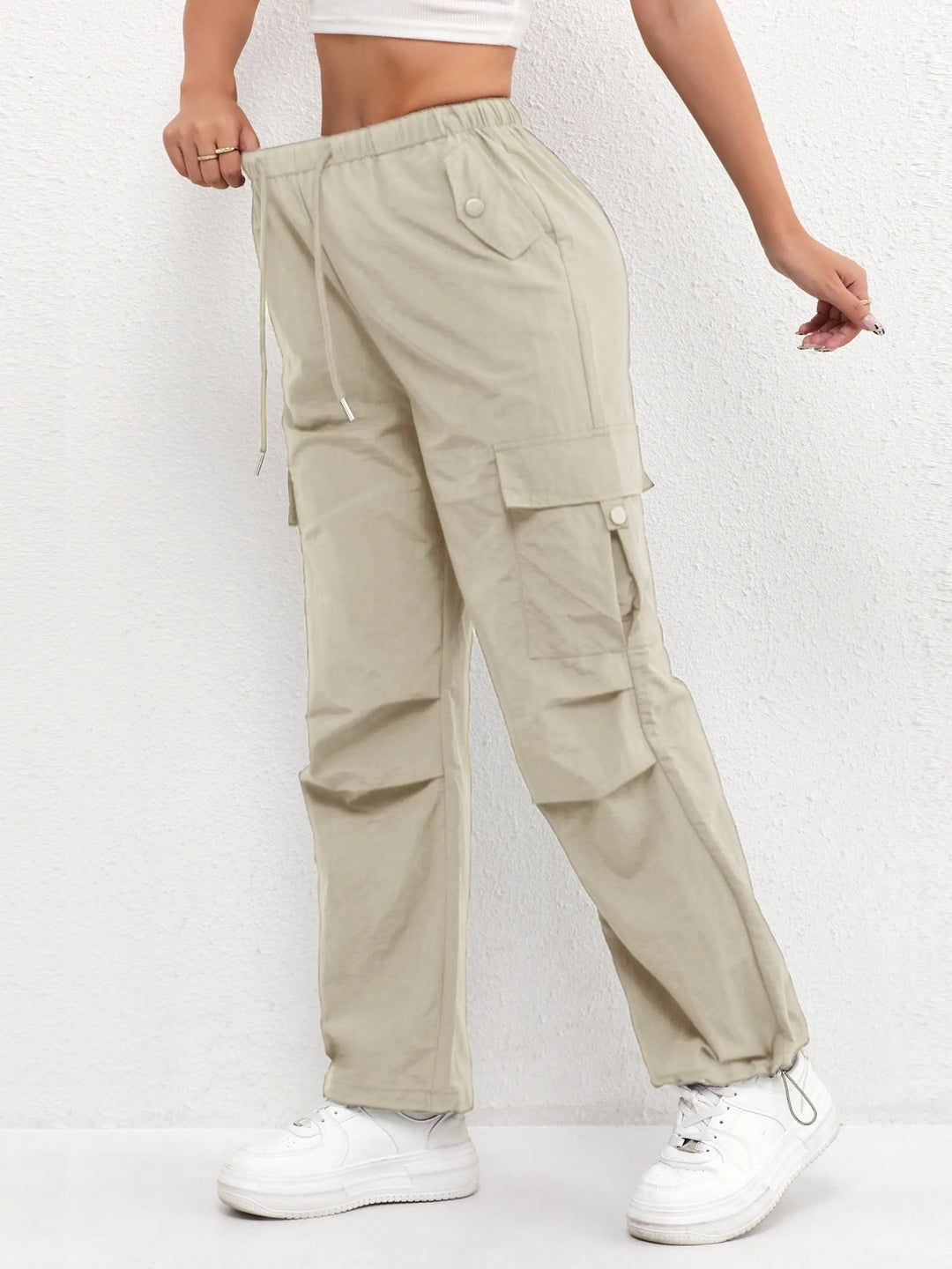 Woman walking in relaxed fit parachute cargo trousers, showcasing flowy fabric, roomy legs & practical side pockets.
