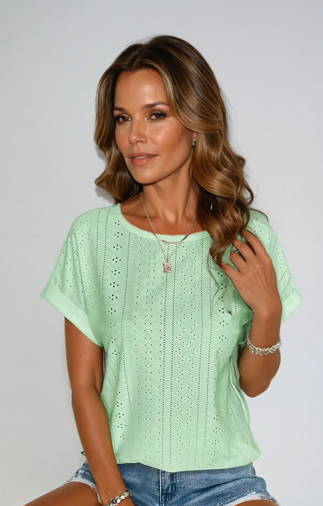 Ladies' eyelet short sleeve top with a crew neck and cuffed sleeves, great for versatile spring wear.