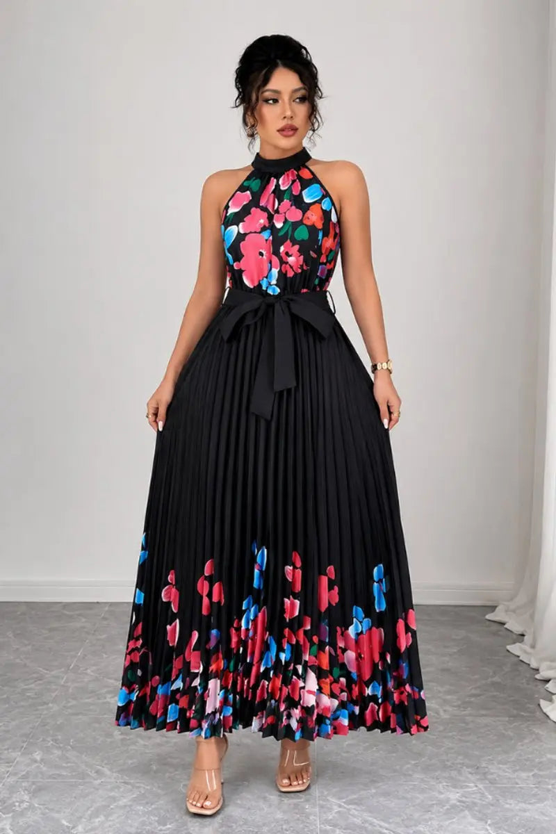 Woman posing in a flowing floral pleated halter neck maxi evening gown. Perfect party dress.