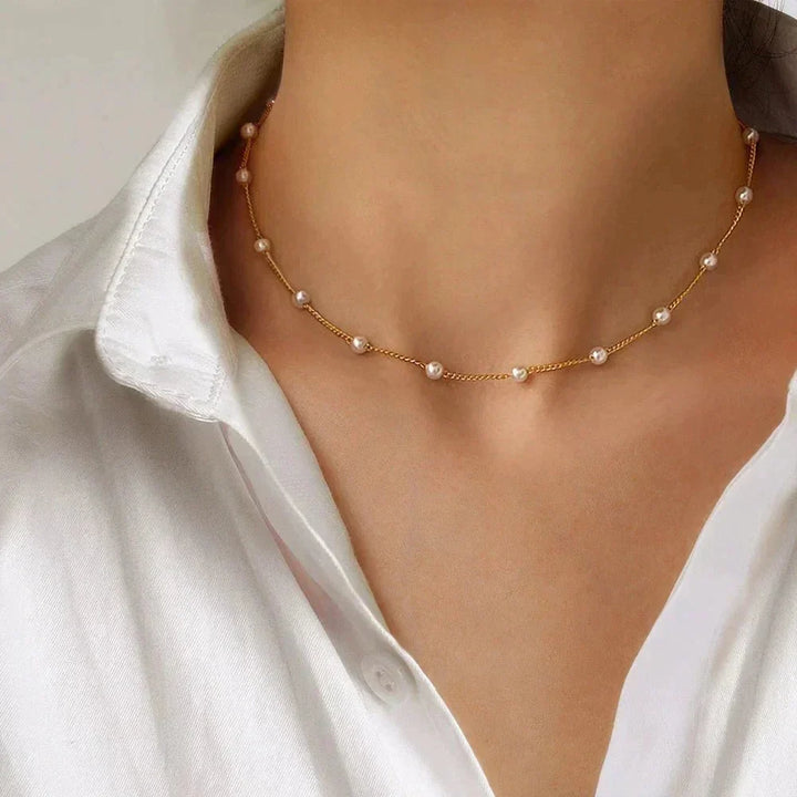 Dainty gold tone choker necklace for women, featuring a single lustrous pearl. Elegant fashion jewelry.