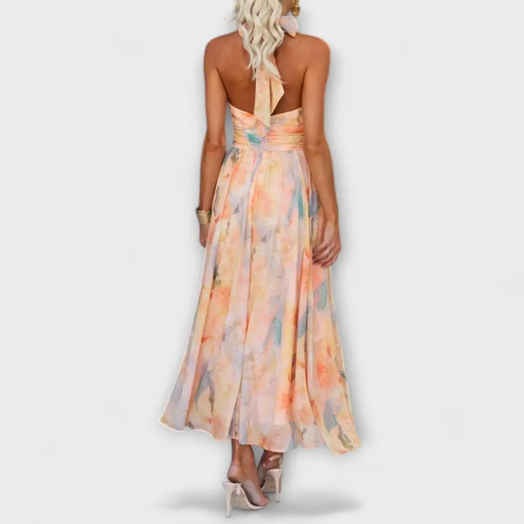 Chic women's flowy watercolor print maxi dress with halterneck and open back, ideal for summer occasions.