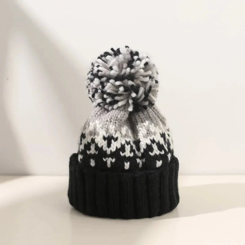 Women's snowflake pom-pom beanie with a cozy ribbed cuff, perfect for winter warmth and festive style.
