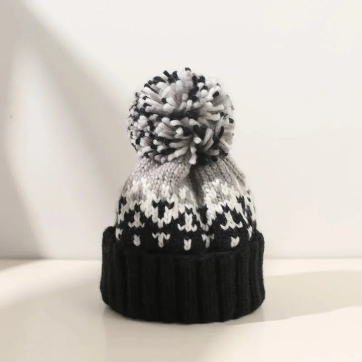 Women's snowflake pom-pom beanie with a cozy ribbed cuff, perfect for winter warmth and festive style.