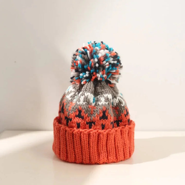 Warm women's headwear: a soft pom-pom beanie with intricate snowflake knit details and a snug ribbed cuff.