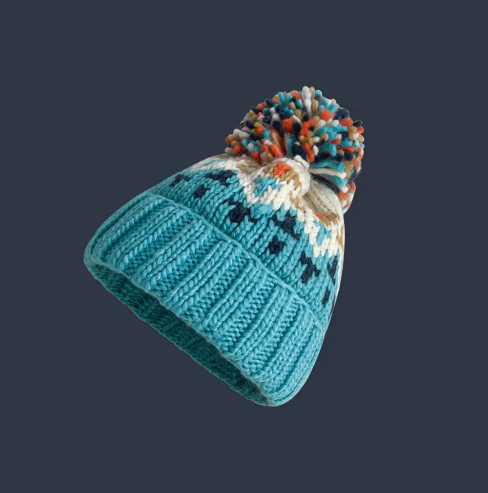 Comfortable women's one-size beanie, decorated with a charming snowflake motif, a playful pom-pom & ribbed cuff.