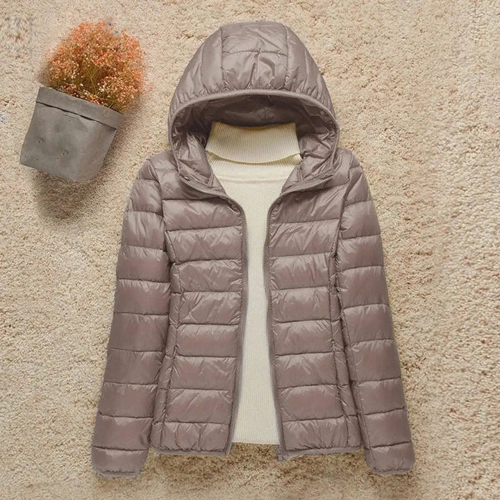 Women's lightweight hooded quilted puffer jacket, packable for travel and outdoor adventures.
