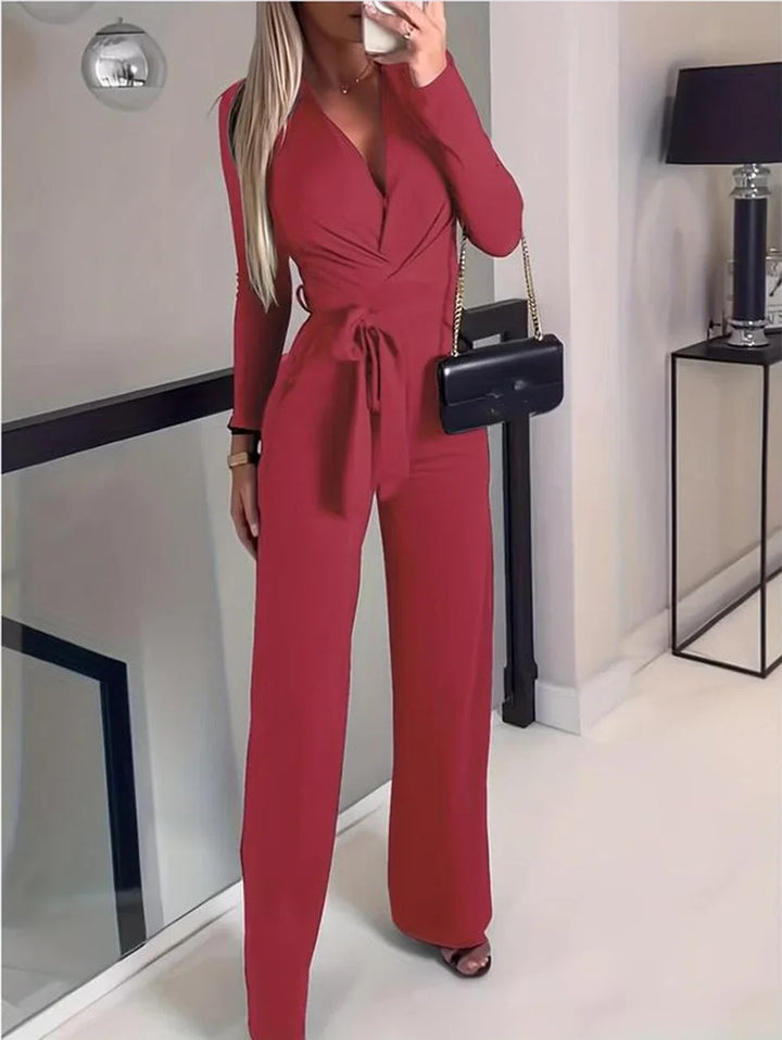 Stylish women's jumpsuit with a V-neck, long sleeves, and wide legs. Accented with a flattering tie-waist. One-piece.