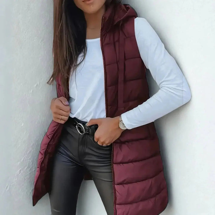 Elegant women's longline hooded puffer vest, a comfortable & warm layering piece for cold weather.
