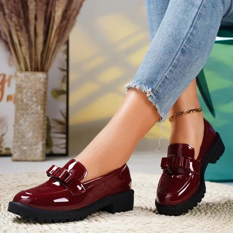 Chic black patent leather slip-on loafers for women, with a decorative bow & comfortable chunky lug sole. Orthopedic design.