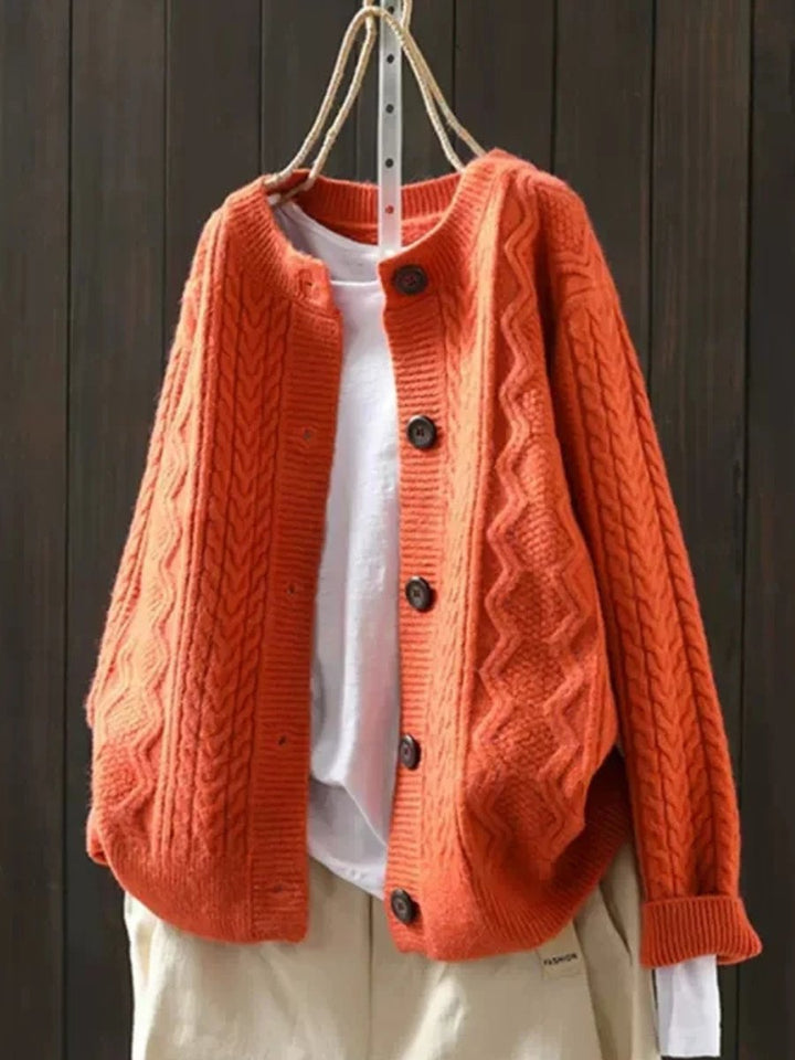 Back view of an oversized women's cable-knit button-down cardigan, showcasing elegant drape and cozy winter style.