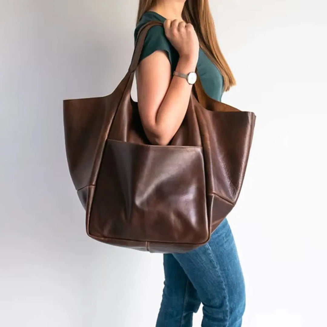 Oversized black vegan leather shoulder bag, magnetic snap closure, versatile.