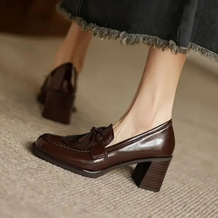Side view of elegant black women's tassel loafer pumps. Features a comfortable block heel & classic round toe design.