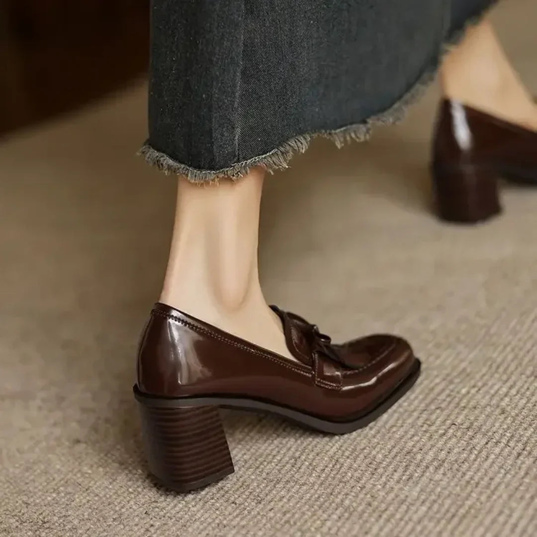 Polished black women's tassel loafer pumps. Elegant block heel, round toe design, comfortable classic professional office shoes.