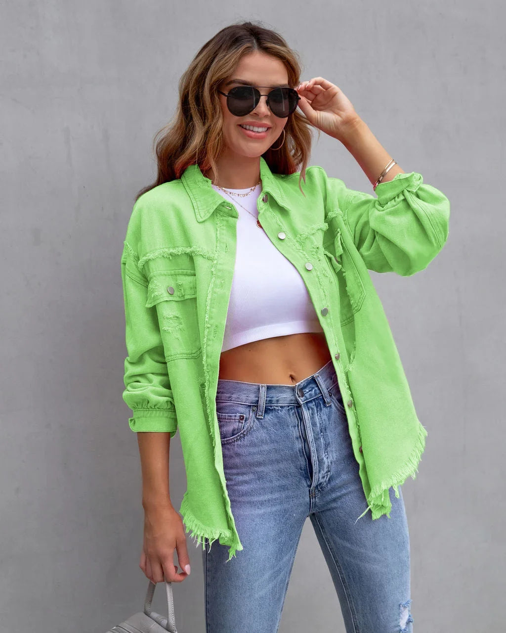 Vibrant pink distressed denim jacket for women, with a unique frayed hem & classic button-front. Stylish outerwear.