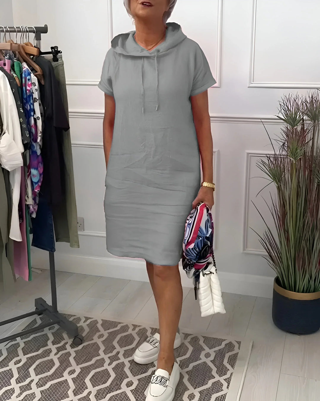 Model in a black short sleeve hoodie mini dress with pockets, a stylish and comfy summer outfit.